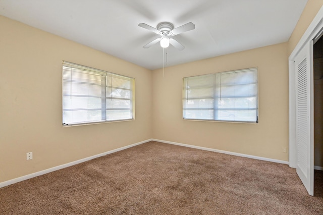 unfurnished bedroom featuring multiple windows, ceiling fan, a closet, and carpet