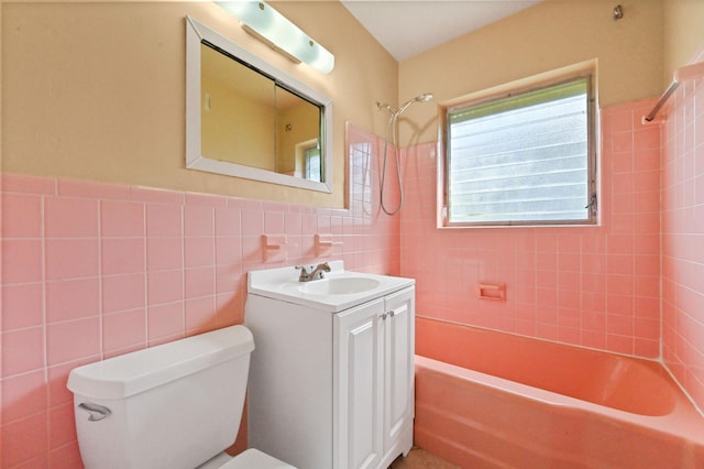 full bathroom featuring tiled shower / bath, vanity, toilet, and tile walls