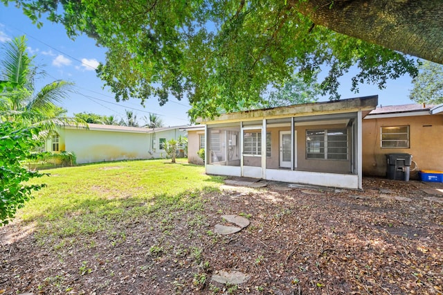 rear view of property featuring a lawn and a sunroom