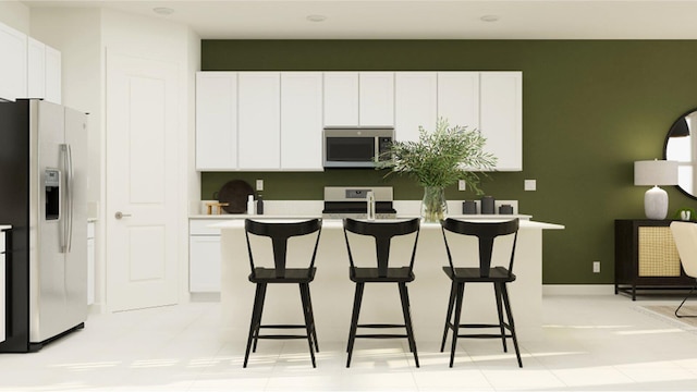 kitchen featuring a breakfast bar, stainless steel appliances, white cabinetry, and light tile patterned floors