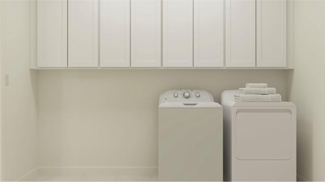 laundry room with cabinets, light tile patterned flooring, and washer and clothes dryer