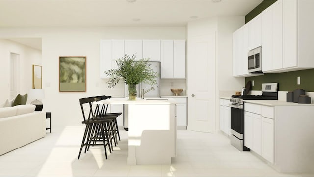 kitchen featuring white cabinets, appliances with stainless steel finishes, a kitchen bar, and a center island