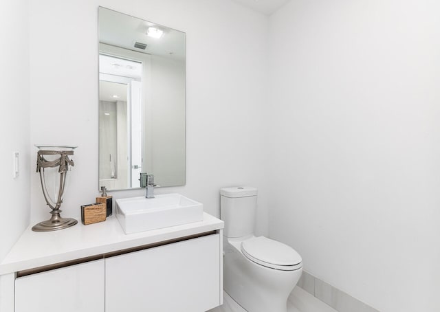 half bath with visible vents, vanity, and toilet