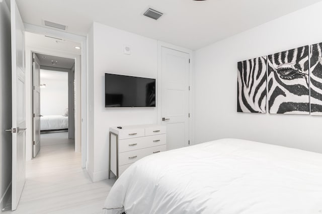 bedroom with light wood-type flooring, visible vents, and baseboards