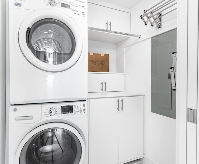 washroom featuring stacked washer and dryer, electric panel, and cabinet space