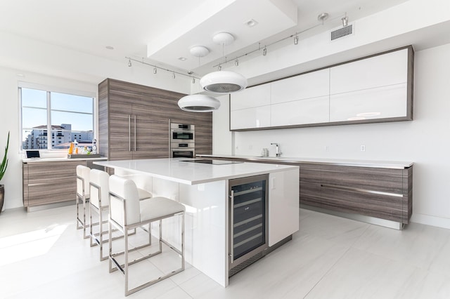 kitchen featuring beverage cooler, a breakfast bar, light countertops, a large island, and modern cabinets