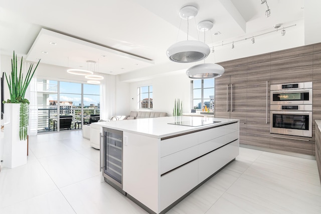 kitchen with black electric stovetop, stainless steel double oven, beverage cooler, a center island, and modern cabinets