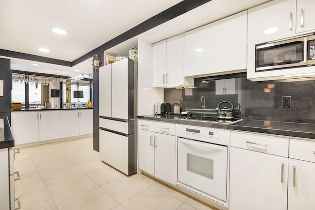 kitchen featuring white cabinetry, backsplash, white oven, black cooktop, and fridge