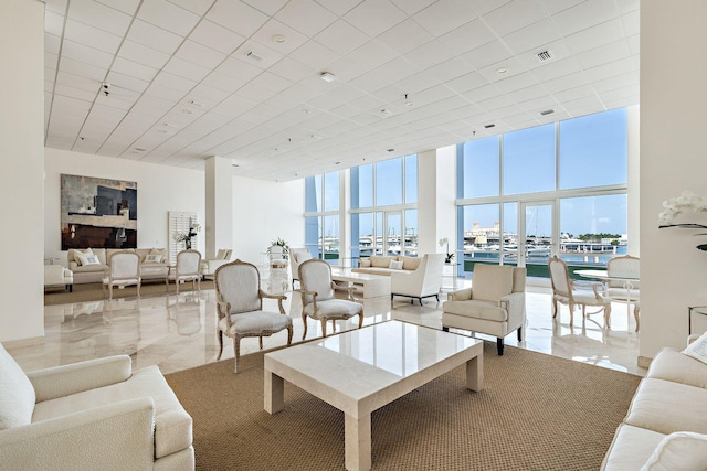 living room featuring a towering ceiling, a water view, and expansive windows