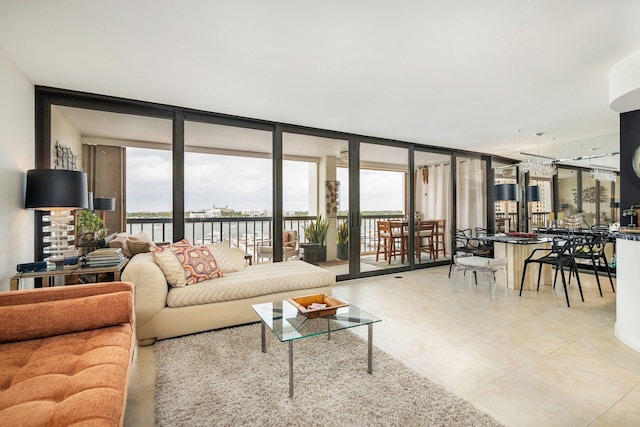 living room featuring a wealth of natural light, a water view, and a wall of windows