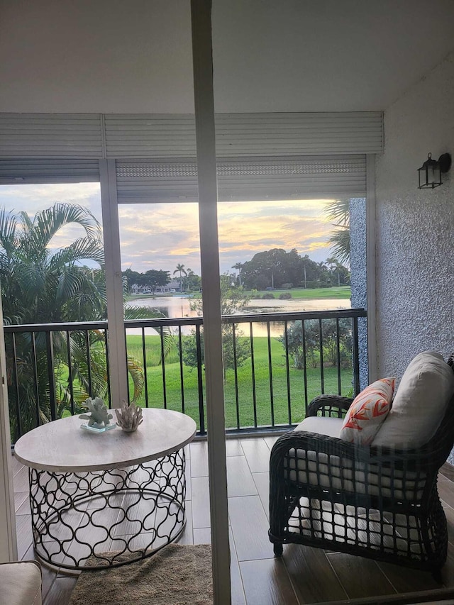 balcony at dusk featuring a water view