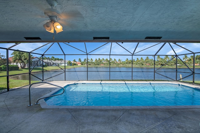 view of swimming pool featuring a water view, a patio area, a lanai, and ceiling fan