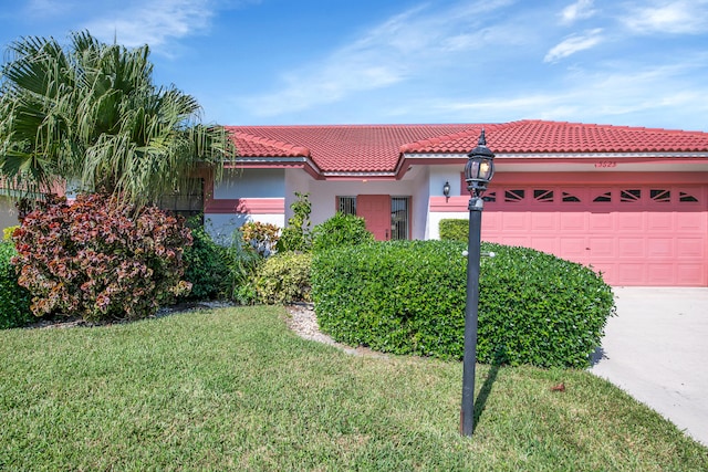 mediterranean / spanish-style home featuring a front lawn and a garage