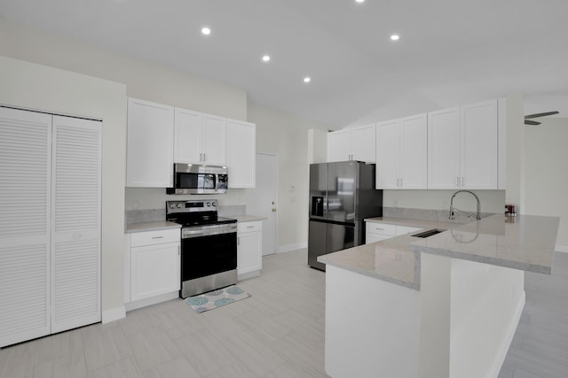 kitchen featuring a peninsula, appliances with stainless steel finishes, light stone counters, and white cabinets