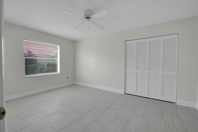 unfurnished bedroom with a ceiling fan, baseboards, a textured ceiling, and a closet