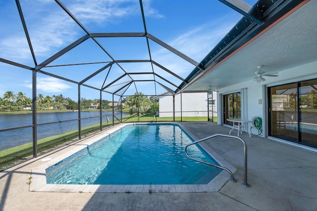 pool with a patio, a ceiling fan, glass enclosure, and a water view