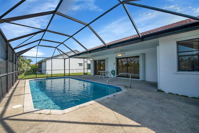 pool with glass enclosure, a patio area, and a ceiling fan