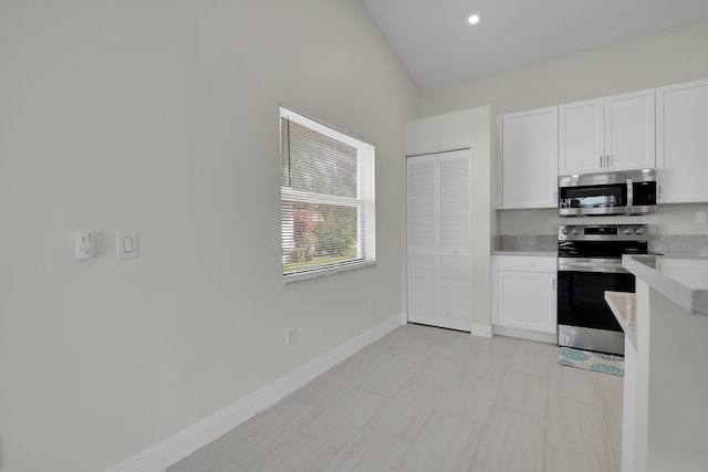 5625 Aspen Ridge Cir, Delray Beach, FL 33484 - kitchen with stainless steel appliances, light countertops, white cabinetry, vaulted ceiling, and baseboards
