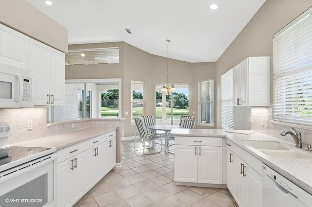 kitchen featuring lofted ceiling, white appliances, a healthy amount of sunlight, and decorative light fixtures