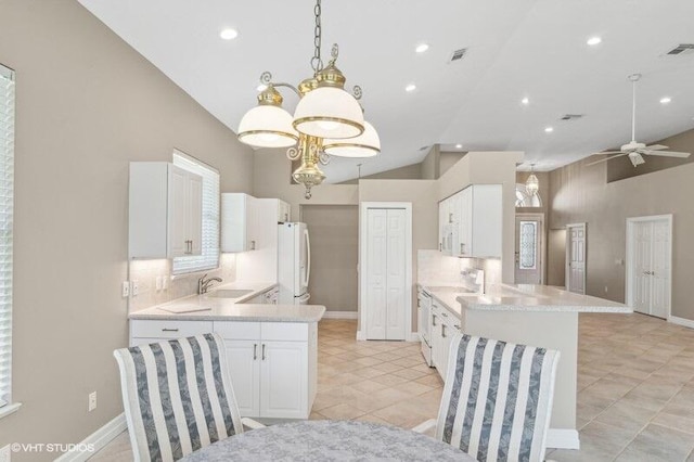 kitchen with white cabinetry, ceiling fan with notable chandelier, kitchen peninsula, white fridge, and sink