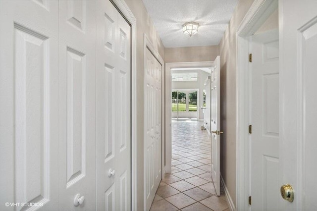 corridor featuring a textured ceiling and light tile patterned floors