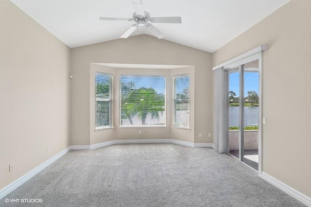 spare room with light carpet, a water view, ceiling fan, and plenty of natural light