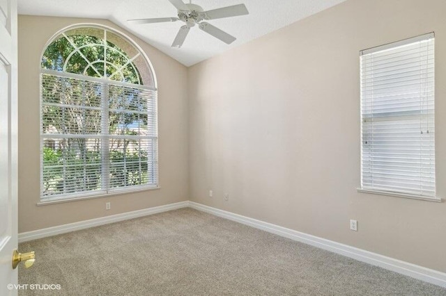 carpeted spare room featuring vaulted ceiling and ceiling fan