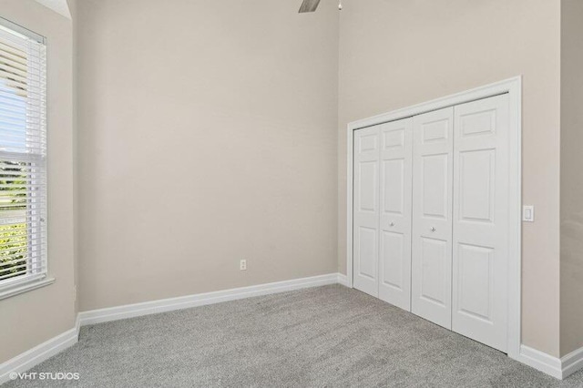 unfurnished bedroom with ceiling fan, light colored carpet, and a closet