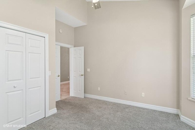 unfurnished bedroom featuring ceiling fan, light carpet, and a closet