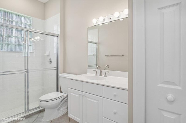 bathroom with vanity, toilet, a shower with door, and tile patterned floors