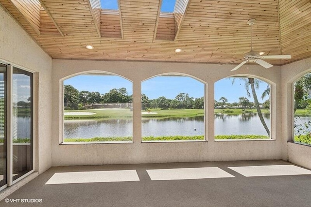 unfurnished sunroom featuring ceiling fan, a skylight, a water view, and a wealth of natural light