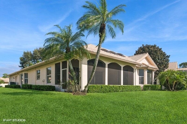 view of side of home with a yard, a sunroom, and central AC unit