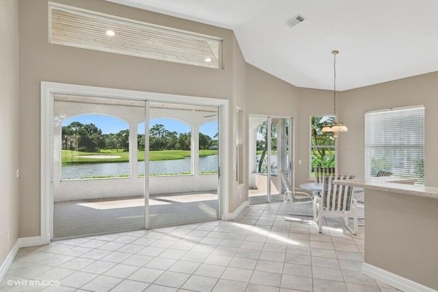 interior space with plenty of natural light, light tile patterned floors, a water view, and high vaulted ceiling