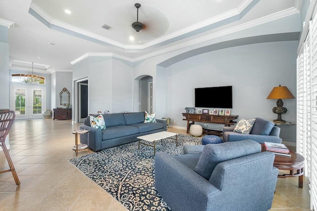 living room featuring a tray ceiling, light tile patterned floors, and ornamental molding