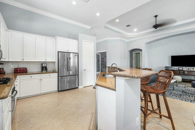 kitchen with sink, appliances with stainless steel finishes, white cabinetry, and a raised ceiling