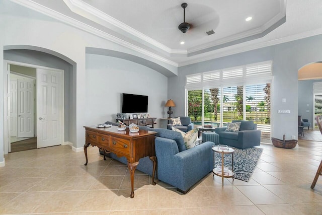 living room featuring a towering ceiling, ceiling fan, crown molding, a tray ceiling, and light tile patterned floors