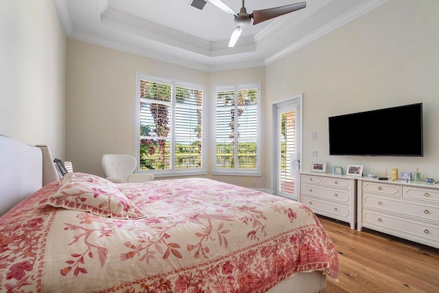 bedroom featuring ornamental molding, light hardwood / wood-style floors, and a raised ceiling