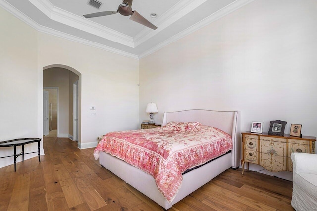 bedroom with a raised ceiling, ceiling fan, hardwood / wood-style flooring, and crown molding