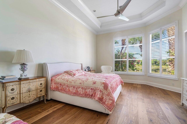 bedroom featuring a tray ceiling, ornamental molding, hardwood / wood-style flooring, and ceiling fan