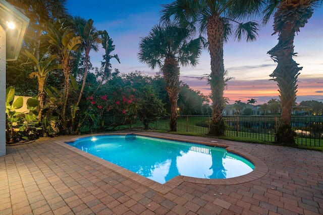 pool at dusk featuring a patio area