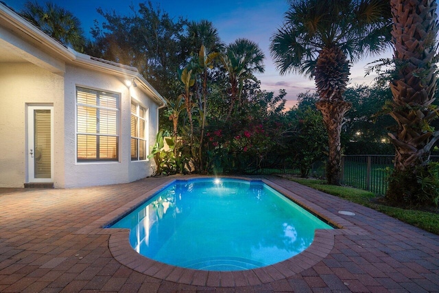 pool at dusk featuring a patio