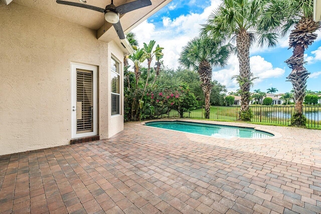 view of pool with a water view, ceiling fan, and a patio area