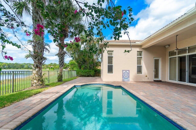 view of pool featuring a water view, ceiling fan, and a patio area