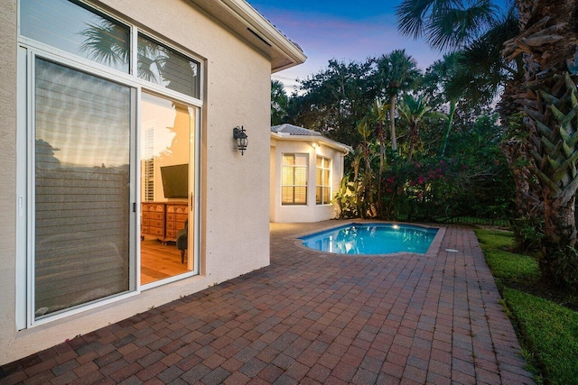 pool at dusk with a patio area