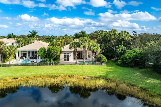 rear view of house with a water view, a patio, and a lawn