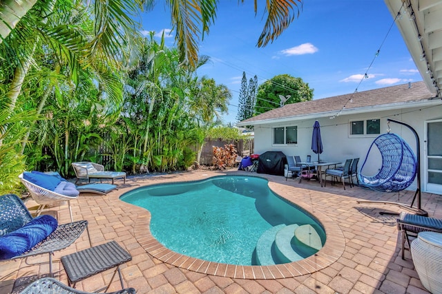 view of pool with grilling area and a patio area