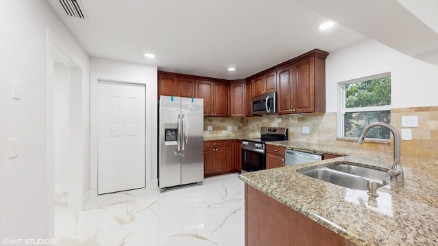 kitchen with sink, kitchen peninsula, backsplash, appliances with stainless steel finishes, and light stone countertops