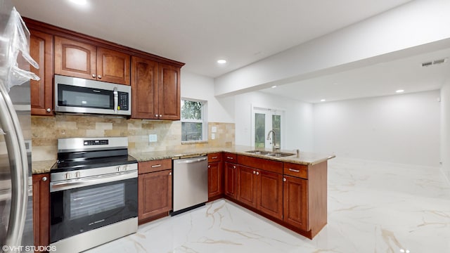 kitchen with light stone countertops, sink, appliances with stainless steel finishes, and kitchen peninsula