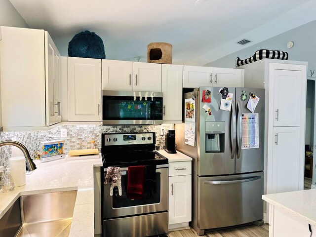 kitchen with tasteful backsplash, light hardwood / wood-style flooring, sink, white cabinets, and appliances with stainless steel finishes