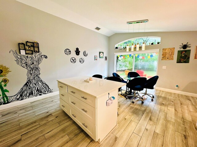 office with light wood-type flooring and vaulted ceiling